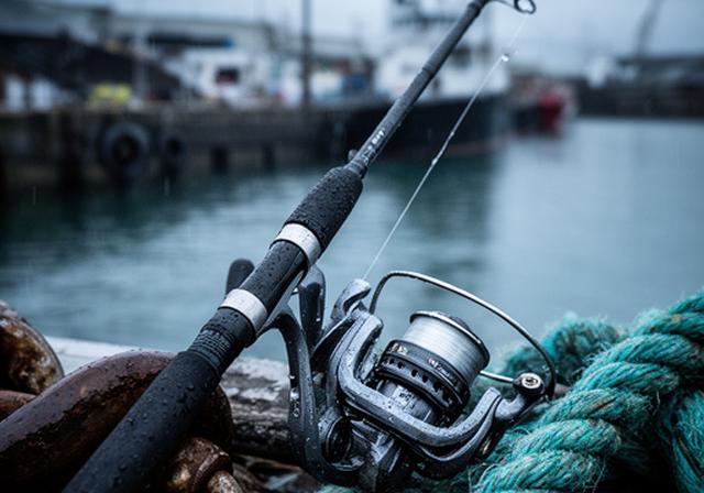 Saltwater fishing reel and rod beside wet dock rope with a protective finish and sealed components